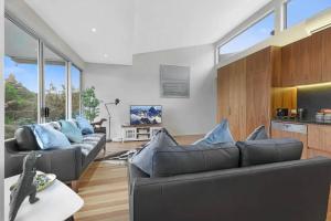 a living room with two couches and a kitchen at Serenity in Central Maleny in Maleny