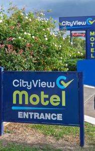 una señal para una entrada de motel en frente de un arbusto en City View Motel, en Warwick