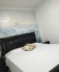 ein Schlafzimmer mit einem weißen Bett und einem Gemälde an der Wand in der Unterkunft HABITACIÓN CERCA AL CENTRO DE SANTA MARTA in Santa Marta