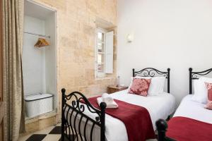 a bedroom with two beds with red and white pillows at Traditional & Modern Maltese Townhouse - Rooftop Terrace and Sea Views, close to Birgu Waterfront in Cospicua