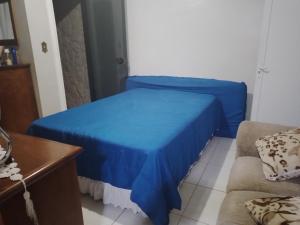 a bedroom with a blue bed and a couch at CANTINHO VOLTE SEMPRE in Aparecida