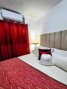 a bedroom with a large bed with red curtains at Como en Casa in Mandinga