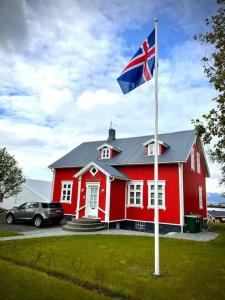 una casa roja con una bandera delante de ella en The Foreman house - an authentic town center Villa, en Húsavík