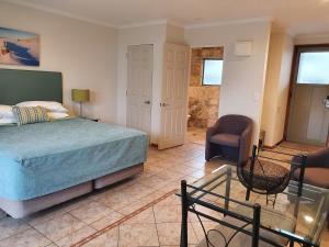 a bedroom with a bed and a chair and a table at Breakers Motel in Whangamata +34 photos