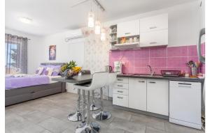 a kitchen with white cabinets and a purple tile wall at Stunning Apartment In Stara Baska With Wifi in Stara Baška