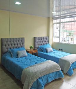 2 camas con sábanas azules en una habitación en Roma Lodges House- Campin Simón Bolivar Movistar Embajada compensar, en Bogotá
