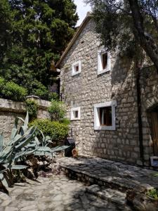 a stone house with white windows and a stone walkway at Villa Golda in Petrovac na Moru