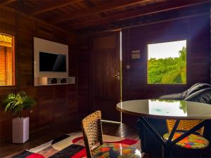 a living room with a table and a tv at Chalé do Beijo in Nazaré Paulista