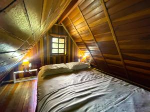a large bed in a wooden room with two lamps at Chalé do Beijo in Nazaré Paulista