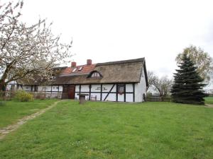 a large white house with a grass yard at Thatched roof house in Pogreß with a large plot 