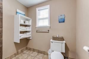 a bathroom with a toilet and a window and towels at Cozy sea breeze bungalow - 2 mins to the beach in Galveston +5 photos