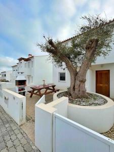 un árbol en una gran plantadora blanca junto a una mesa en Olive Tree Sunset View - V3 luxo vista mar, en Aljezur