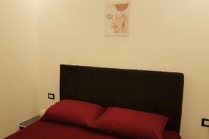 uma cama com uma cabeceira preta e uma almofada vermelha em ستوديو فندقي مع مسرح منزلي روعه وواي فاي em ‘Ezbet `Abd el-Ḥamîd