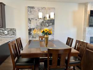 a dining room table with chairs and a vase of flowers at Apple House- New Townhouse - 2 Car Garage by CCBC & Franklin Sq in Rosedale