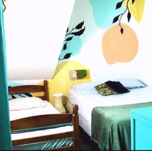 a bedroom with two beds and a tree on the wall at Rio Surf House Hostel e Pousada in Rio de Janeiro