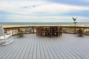 Toes in the Sand في Westhampton Beach: سطح خشبي مع طاولة وكراسي على الشاطئ