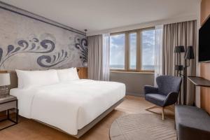 um quarto com uma cama branca e uma cadeira em Frankfurt Marriott Hotel em Frankfurt