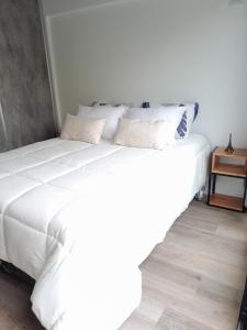 1 cama blanca grande con sábanas y almohadas blancas en Apartamento Nuevo a Estrenar en Buenos Aires