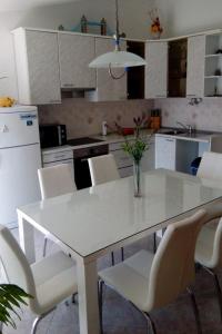 a kitchen with a white table and white chairs at Apartments by the sea Dugi Rat, Omis - 21074 in Dugi Rat