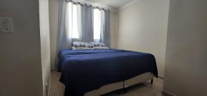 um quarto com uma cama azul e uma janela em Apartamento - Dois Dormitórios - Todo Equipado em Bauru