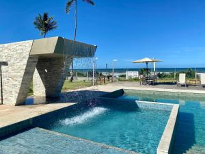 una piscina con una fuente de agua en un complejo en Kalug - Duplex PÉ NA AREIA com 4 suítes, piscina e churrasqueira privativa na Praia do Sul! Perfeito para família - Wifi 300mb! en Ilhéus
