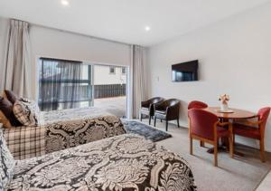 a hotel room with two beds and a table and chairs at Dunrovin Motel in Taupo