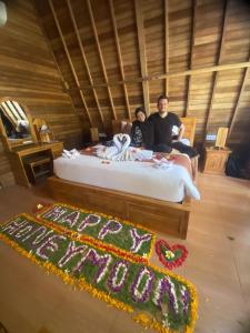 un hombre y una mujer sentados en una cama con un pastel de cumpleaños en Kubu Penida Villa en Nusa Penida
