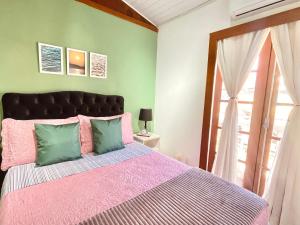 um quarto com uma cama rosa e verde em 1 Quarto Pra 2 Búzios em Búzios