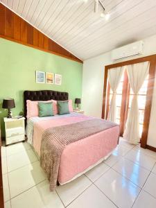 a bedroom with a pink bed and a green wall at 1 Quarto Pra 2 Búzios in Búzios