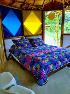 a bed with a colorful comforter in a room at EcoaldeaHotel Aguaviva2 in Aranzazu