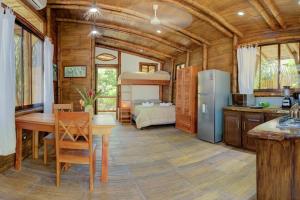 a kitchen with a table and a refrigerator and a bedroom at Sámara Tarantela Houses, Casa Guadua in Sámara