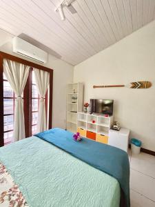 a bedroom with a blue bed and a tv at 1 Quarto Pra 2 Búzios in Búzios