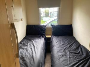 two beds in a small room with a window at Trimingham Static Van in Trimingham