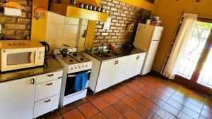 a kitchen with a stove and a microwave at Casa Quinta Rodeada de Bodegas Piscina BBQ Mendoza in Maipú