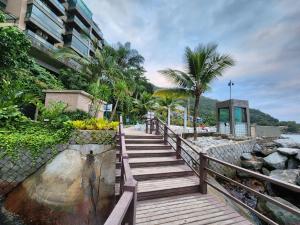 a wooden staircase leading to a beach with palm trees at AP Alecrim Porto Real Suítes com Tela de Proteção Praia Privativa in Mangaratiba