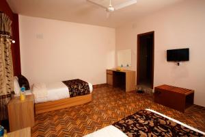 Sauraha Holiday Home Riverside في شيتوان: غرفة فندقية بسريرين وتلفزيون بشاشة مسطحة