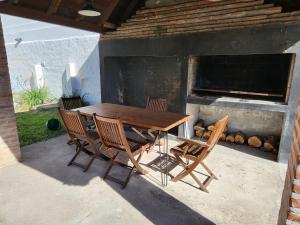 een houten tafel en stoelen op een terras bij Casa familiar con parrilla y patio compartido in Tandil
