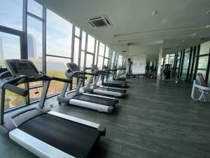 une rangée de tapis de course dans une salle de sport avec fenêtres dans l'établissement Southkey Mosaic near Midvalley-B33 bathtub & Mahjong- Super High floor, à Johor Bahru