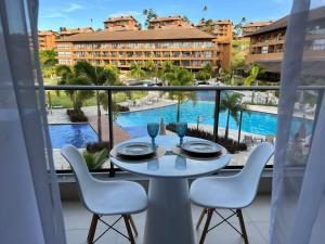 a table and chairs on a balcony with a view of a pool at Flat com vista linda Eco Resort in Tamandaré