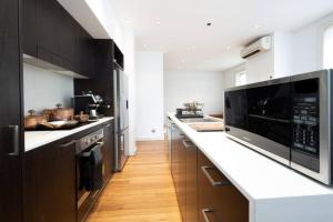 a kitchen with black cabinets and a white counter top at Eggie's Nest - Luxurious City Apartment in Sydney