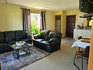 a living room with a black leather couch and a table at Riverview Lodge in Hanmer Springs