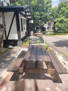 una mesa de picnic de madera frente a una casa en Hakuba Matata Apartment, en Hakuba