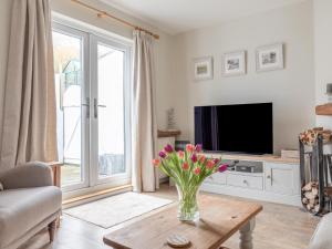 una sala de estar con un jarrón de flores sobre una mesa de centro en 1 Top View Cottages, en Salcombe