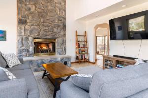 a living room with a stone fireplace with a tv at Spacious Cabin with Private Covered Hot Tub in Albrightsville