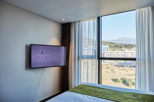 1 dormitorio con ventana grande y TV en la pared en Jeju Pureun Hotel en Seogwipo