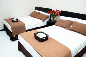 ein Hotelzimmer mit drei Betten und einer Vase mit Blumen in der Unterkunft Hotel Paris in Machala