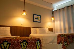 a hotel room with two beds and two lights at Pousada Ubuntu in Ubatuba