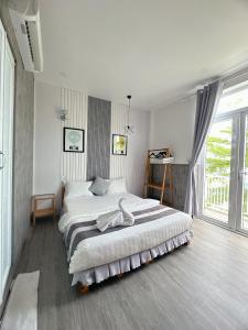 a bedroom with a large bed and a large window at Sele House in Hà Tiên