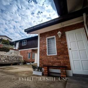 cofyhill cottage في Gopeng: منزل من الطوب مع باب مرآب أبيض