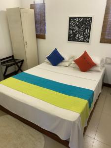 a bed with colorful pillows on it in a room at Settle Inn Tourist Lodge in Kandy